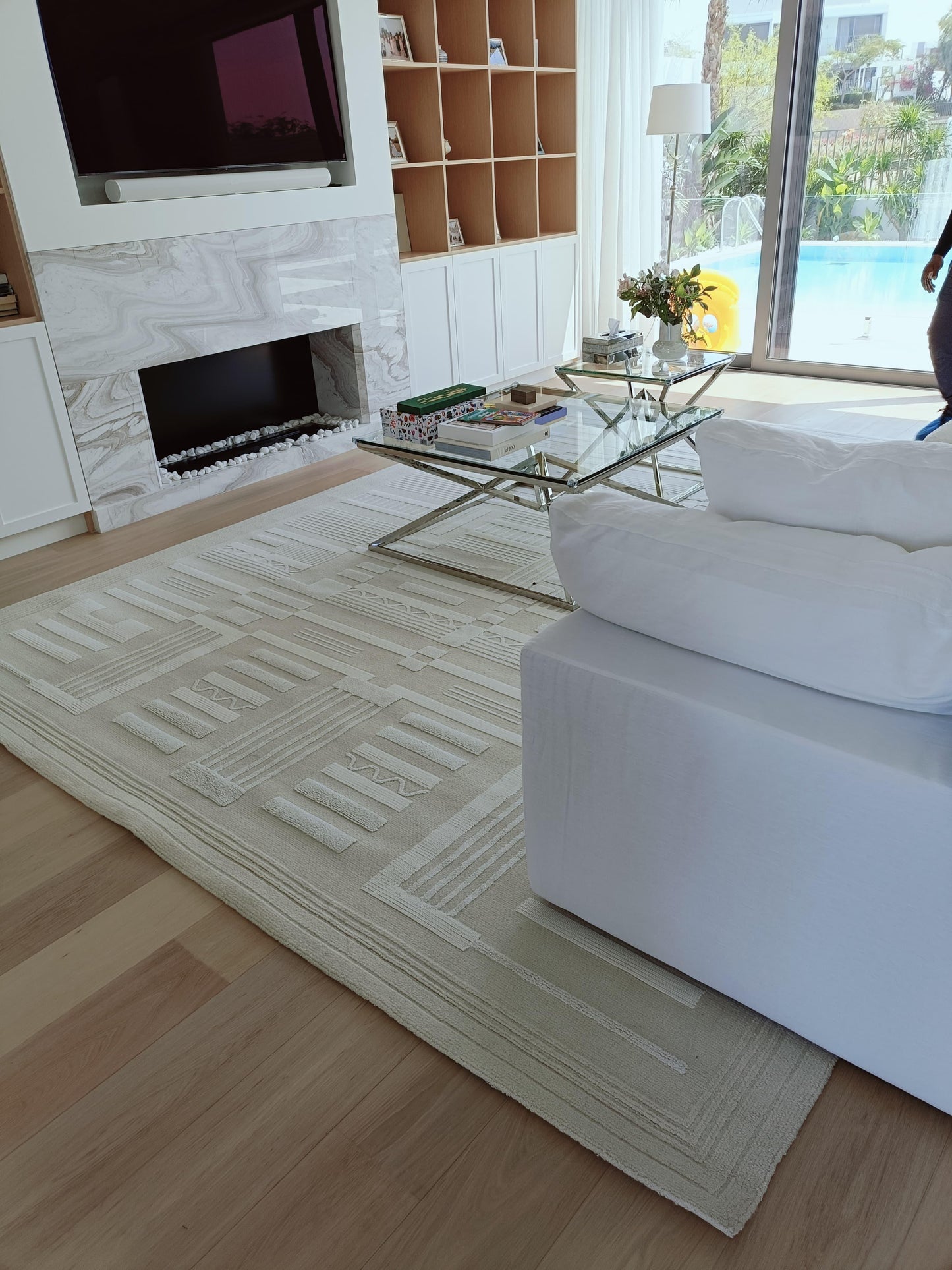 Modern living room with white sofa, glass coffee table, and marble fireplace.