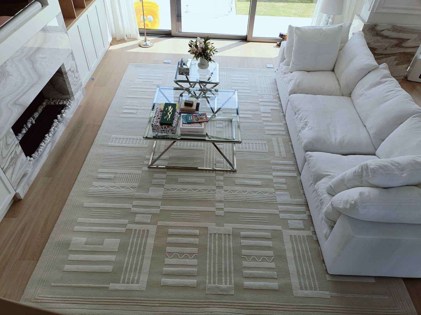 Living room with a white sofa, glass coffee table, and patterned rug.