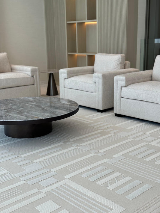 Modern living room with gray upholstered chairs and a round coffee table on a patterned carpet.