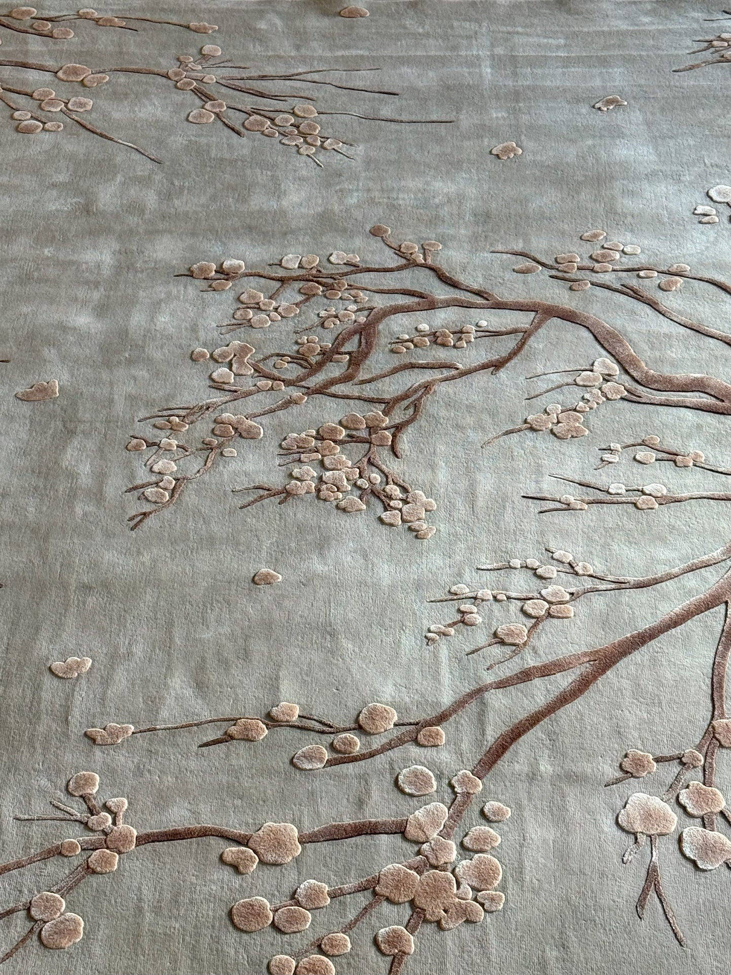 Embroidered floral design on fabric with brown branches and pink flowers.