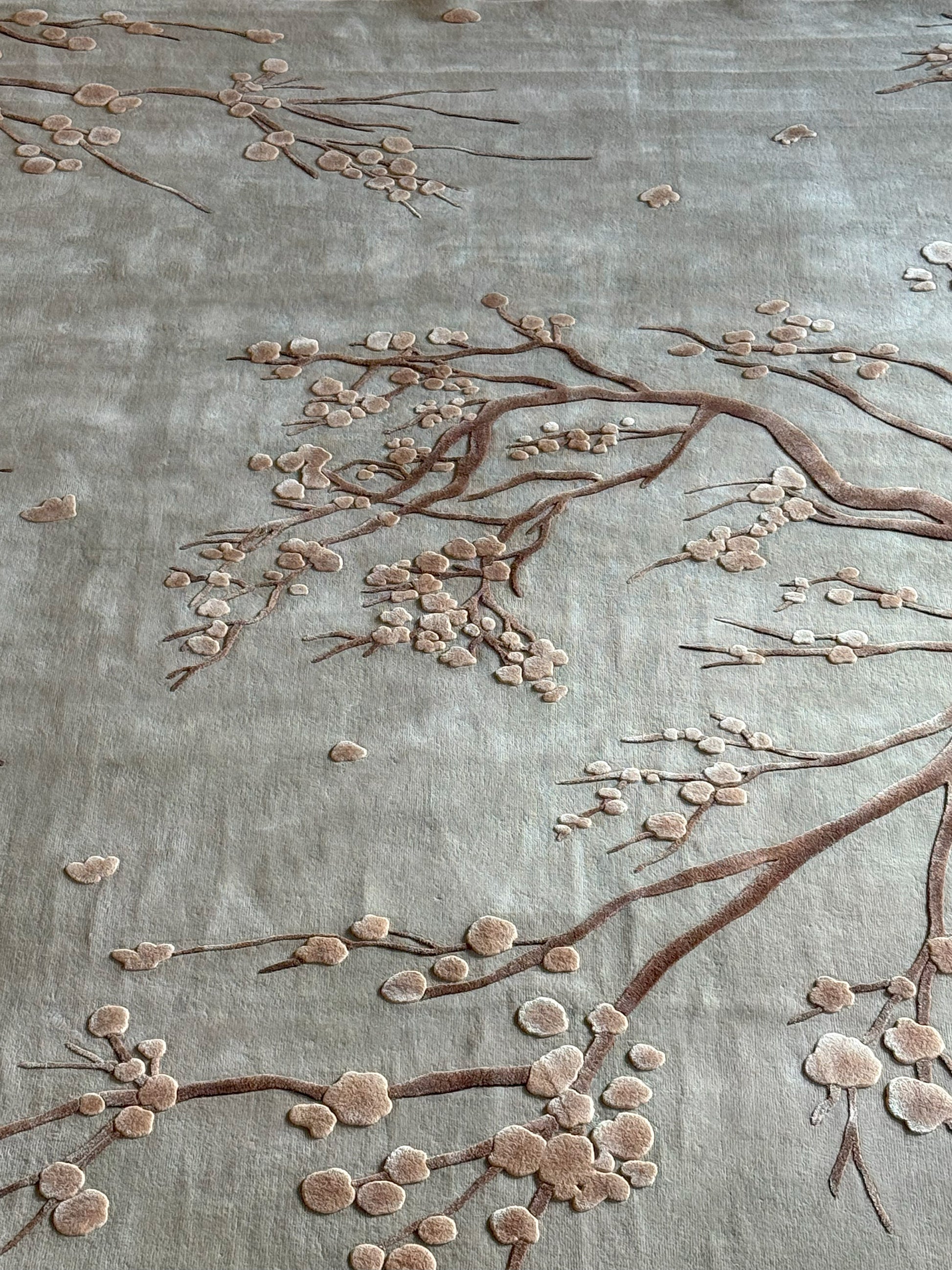 Embroidered floral design on fabric with brown branches and pink flowers.