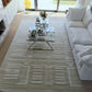 Living room with a white sofa, glass coffee table, and patterned rug.