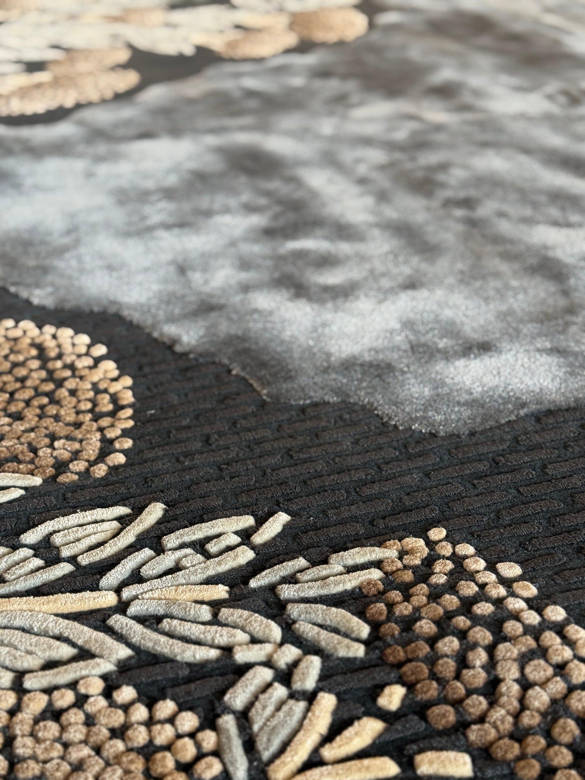 Close-up of a textured rug with geometric patterns in black, gold, and gray.