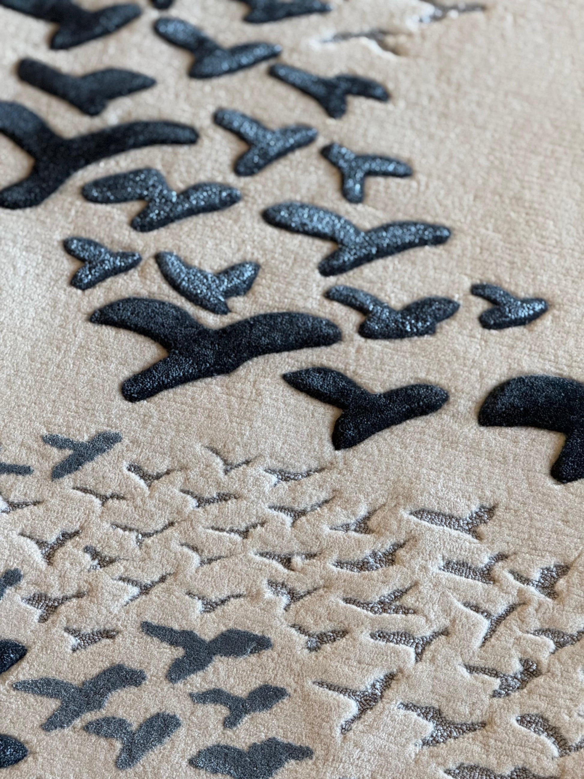 Pattern of black birds on a beige sand background