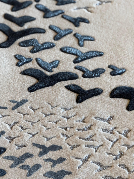 Pattern of black birds on a beige sand background