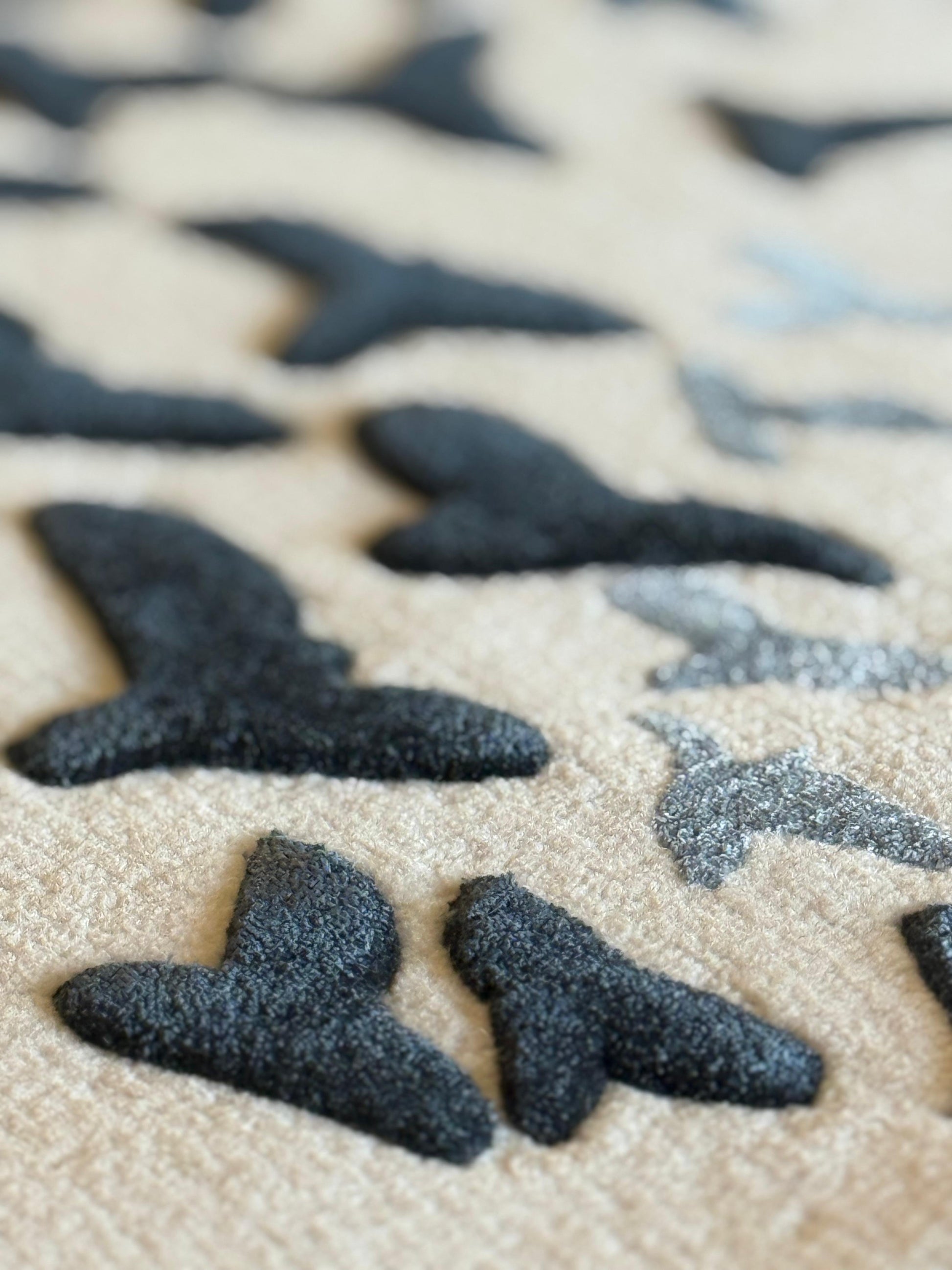 Close-up of black shark-shaped objects on a beige surface