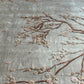 Embroidered floral design on fabric with brown branches and pink flowers.