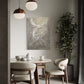 Dining room with a round table, chairs, and abstract art on the wall.